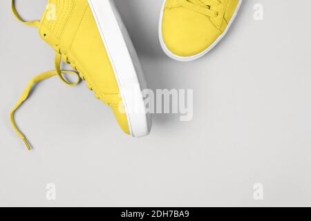 Sneaker gialle su sfondo grigio. Foto a colori, colori dell'anno 2021 illuminanti e Ultimate Grey. Foto Stock