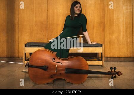 Adolescente con il suo violoncello, in posa in una sala. Foto Stock