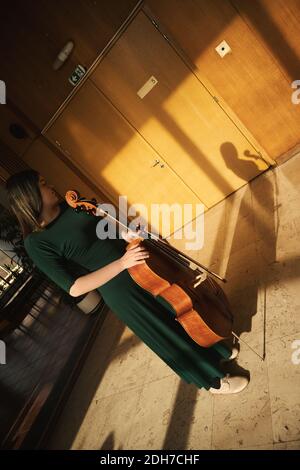 Adolescente con il suo violoncello, in posa in una sala. Foto Stock