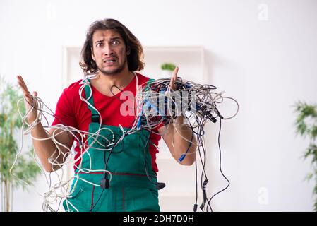 Divertente giovane elettricista maschile che lavora in interni Foto Stock