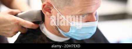 Giovane uomo in maschera protettiva sul viso fa il taglio dei capelli salone di bellezza ritratto Foto Stock