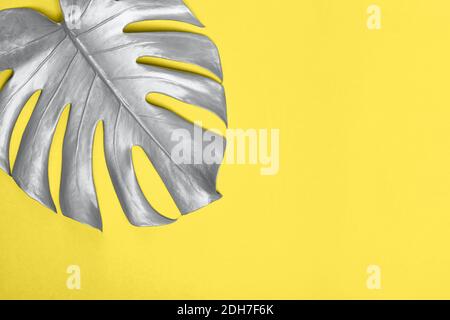 Foglia di monstera argentata su sfondo giallo con spazio per la copia. Modello di progetto con posizione per il testo. Illuminanti e Ultimate Grey Colors dell'anno 2021 Foto Stock