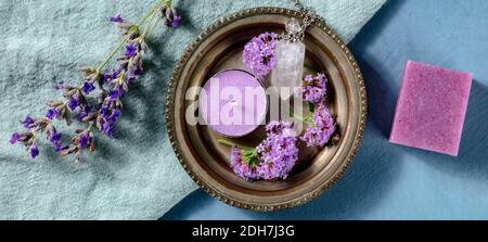 Panorama aromaterapico. Candela profumata, sapone e flaconcino di profumo, sparato dalla parte superiore con fiori vervani e lavanda Foto Stock