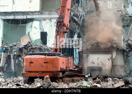 Lavori di demolizione di un vecchio edificio. L'escavatore demolisce un vecchio edificio con attrezzature speciali Foto Stock
