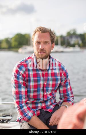 Uomo medio adulto seduto sullo yacht al fiume Foto Stock