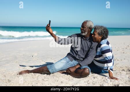 Vecchia coppia che scatta foto in spiaggia Foto Stock