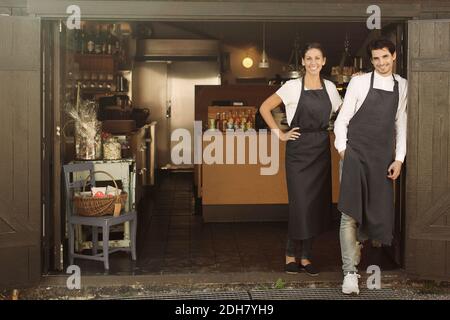 Ritratto a lunghezza intera di proprietari sorridenti che si trovano all'esterno del ristorante Foto Stock