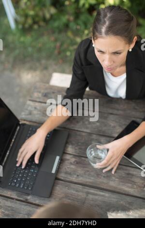 Vista ad alto angolo di una donna d'affari utilizzando un computer portatile presso un caffè all'aperto Foto Stock