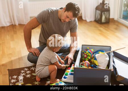 Il padre e il bambino giocano i giocattoli sul pavimento a casa Foto Stock