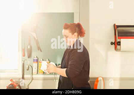 Vista laterale del meccanico femminile che lava le mani in riparazione automatica negozio Foto Stock