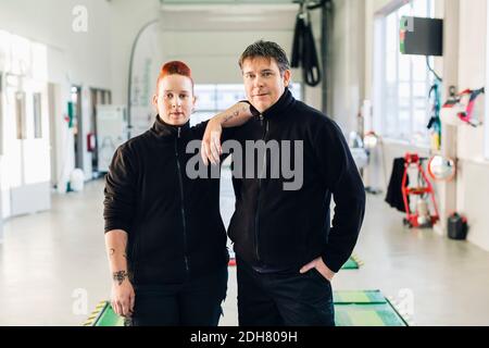 Ritratto di meccanici sicuri in piedi in officina di riparazione auto Foto Stock