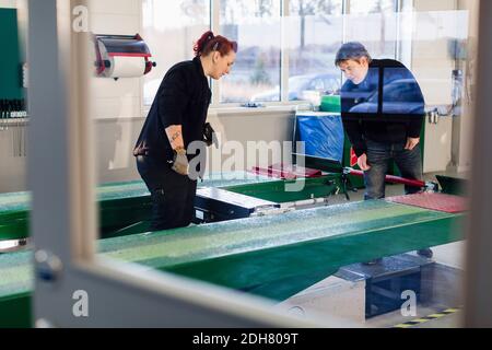 Meccanica maschio e femmina che aziona il sollevatore idraulico in riparazione automatica negozio Foto Stock