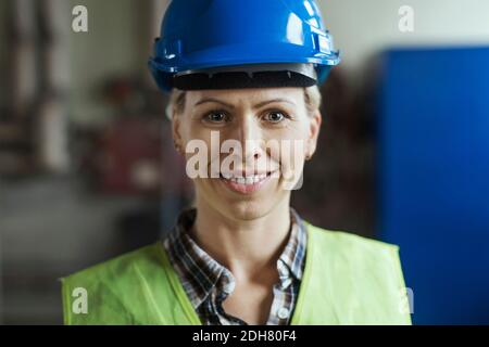 Ritratto di lavoratrice manuale che indossa il cappello in fabbrica Foto Stock