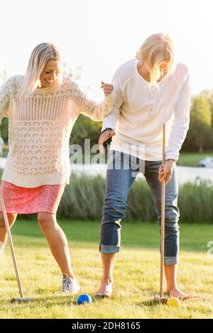 Amici felici che giocano il croquet sul campo Foto Stock