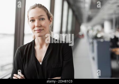Ritratto di fiducioso imprenditrice in piedi in ufficio Foto Stock