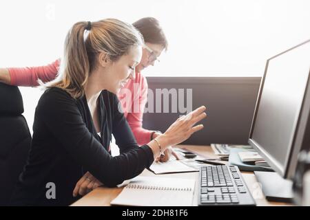 Donne d'affari che discutono alla scrivania del calcolatore in ufficio Foto Stock