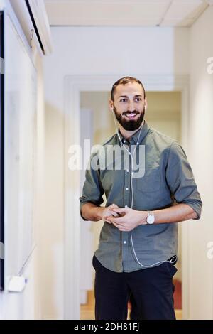 Buon uomo d'affari che ascolta la musica con le cuffie in ufficio Foto Stock
