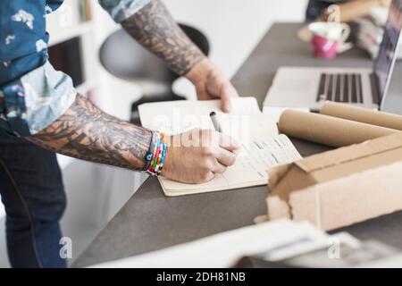 Sezione centrale dell'architetto maschile che scrive nel libro a tavola Foto Stock