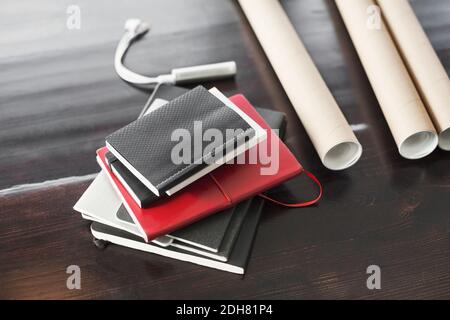 Vista ad alto angolo di libri e blueprint su un tavolo di legno a casa Foto Stock