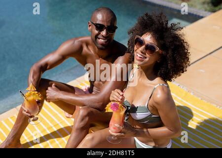 Giovane coppia rilassante vicino alla piscina in una giornata di sole Foto Stock
