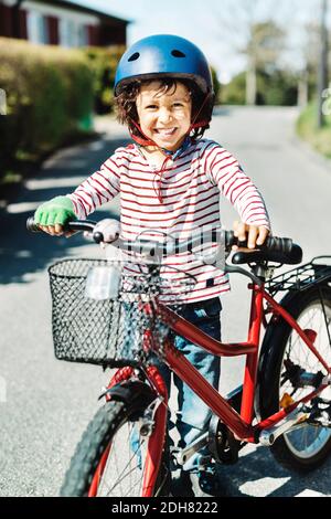 Ritratto di ragazzo felice in piedi con la bicicletta sul sentiero a. iarda Foto Stock