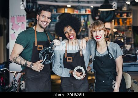 Ritratto di felice meccanica multietnica con attrezzi in officina Foto Stock