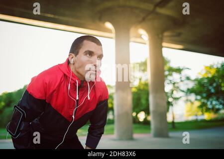 Uomo che indossa una camicia con cappuccio che si piega sulla strada Foto Stock