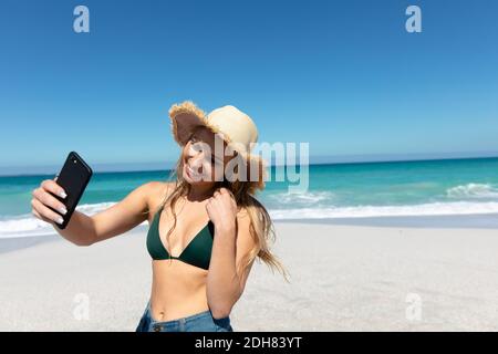 Giovane donna che prende selfie alla spiaggia Foto Stock