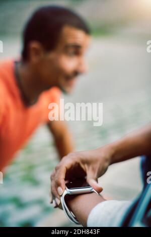 Donna che usa l'orologio intelligente mentre l'uomo fa i push-up Foto Stock