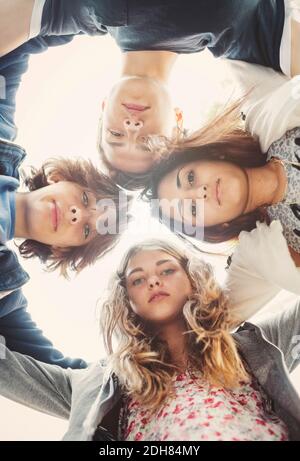 Direttamente sotto ritratto di adolescenti che formano huddle contro il cielo Foto Stock