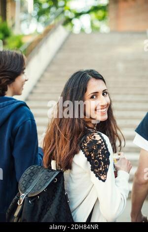 Retrostante ritratto di felice adolescente femmina con amici maschi all'aperto Foto Stock