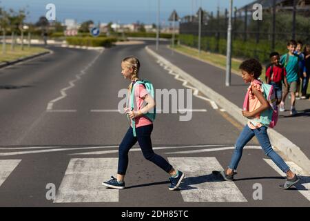 Due studentesse che attraversano la strada su un passaggio pedonale