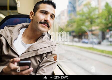 Giovane uomo che guarda attraverso la finestra del tram Foto Stock