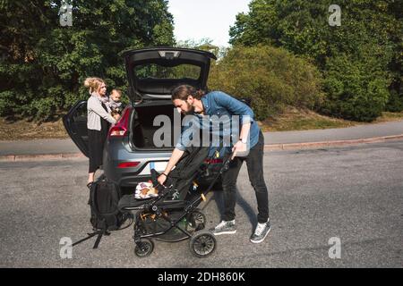 Genitori adulti medi con bambino e passeggino vicino all'auto sulla strada Foto Stock