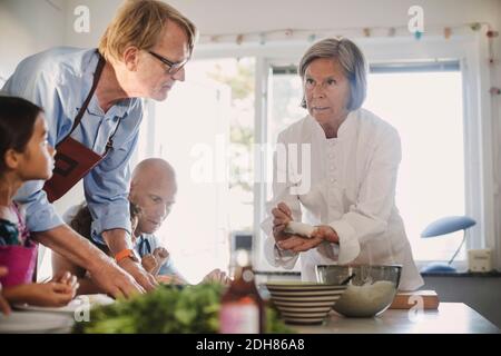 Donna anziana che insegna la famiglia a fare cibo asiatico in cucina Foto Stock