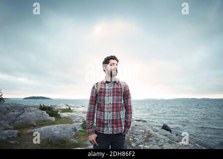 Wonderlust uomo che guarda via mentre si trova sulla roccia dal mare Foto Stock