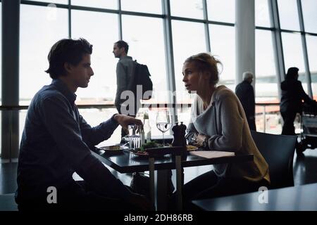 Gli uomini d'affari parlano mentre mangiano al caffè dell'aeroporto Foto Stock