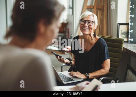 Buon progettista industriale che tiene il prodotto solare mentre discute con il collega in ufficio a casa Foto Stock