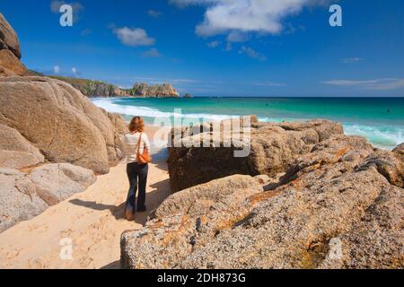 Una signora che cammina sulla bellissima spiaggia della Cornovaglia Porthcurno UK Foto Stock