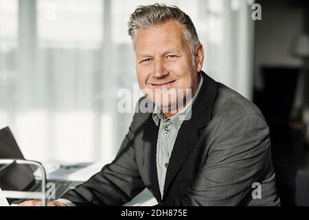 Ritratto di uomo d'affari sorridente seduto in ufficio Foto Stock