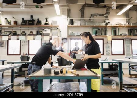 Insegnante che guida lo studente della scuola superiore sul progetto in officina Foto Stock