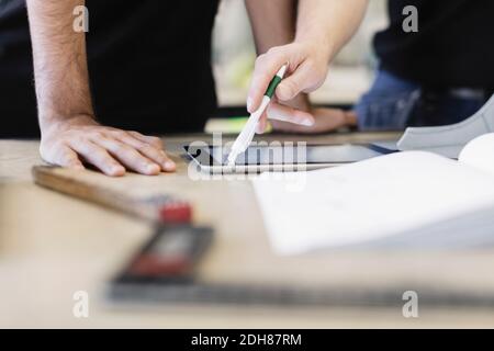 Sezione centrale del partecipante e dell'insegnante che utilizza il tablet digitale al tavolo Foto Stock