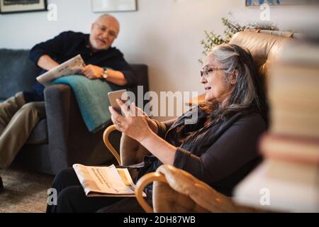 Donna anziana che mostra il telefono cellulare all'uomo a casa Foto Stock
