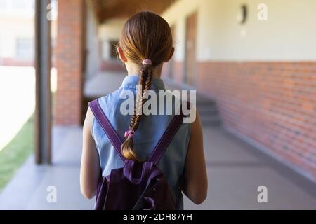 Scolaretta che si trova nel cortile della scuola elementare Foto Stock