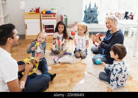 Felici insegnanti e bambini che tengono strumenti musicali in classe Foto Stock