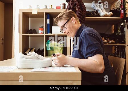 Cassiere di scrittura sul tavolo mentre calcolando in negozio di abbigliamento Foto Stock