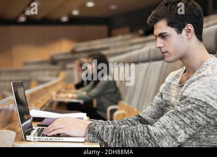 Vista laterale di un bel giovane uomo che utilizza un computer portatile in convenzione centro Foto Stock