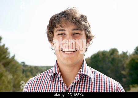 Primo piano ritratto di bel giovane uomo sorridente all'aperto Foto Stock
