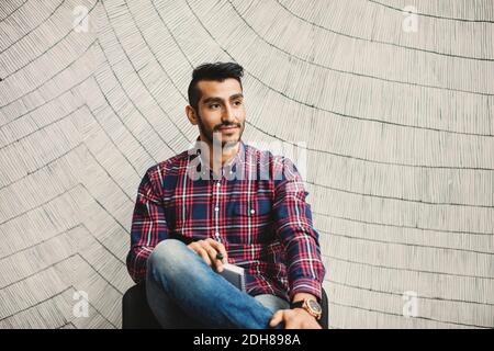 Uomo d'affari premuroso seduto contro il muro in ufficio creativo Foto Stock