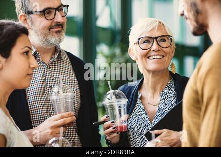 Uomini d'affari multietnici che discutono mentre si hanno rinfreschi in ufficio creativo Foto Stock